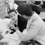 Brigitta Skarpalezos allongée sur un lit avec Victor-Emmanuel Boine de dos expliquant une scène du film.